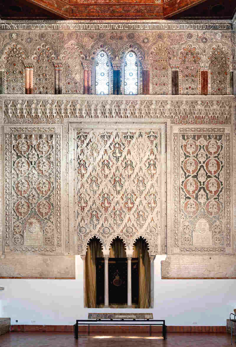 The interior of the 14th-century El Transito synagogue in Toledo, Spain. The synagogue's walls are intricately carved with Hebrew prayers, in marble and gold, and Moorish designs  representing the mix of Jewish and Arab traditions that coexisted in Spain during the Middle Ages. Here you can see the knave of the synagogue, where Torah scrolls were once kept.